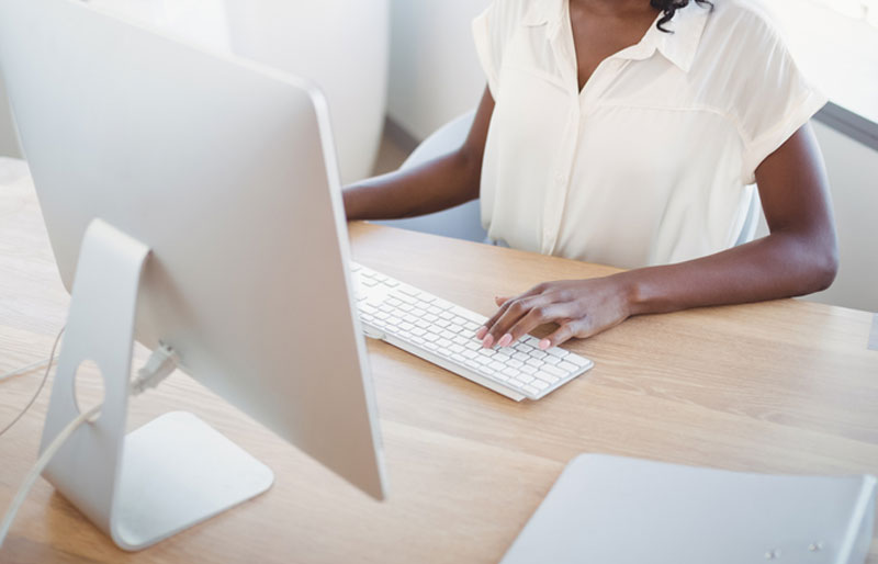 Woman in white on keyboard and looking at monitor