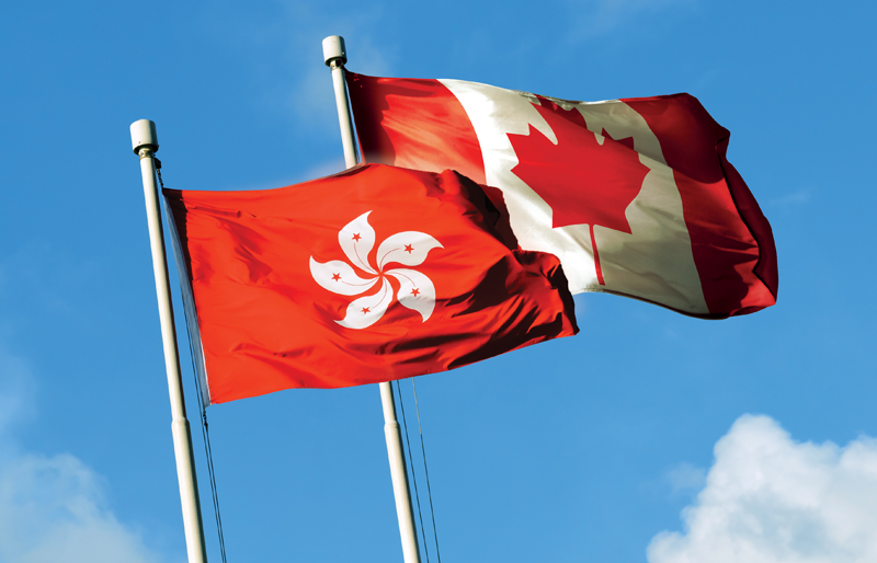 Photo of both the Hong Kong flag and Canadian flag blowing in the breeze side-by-side