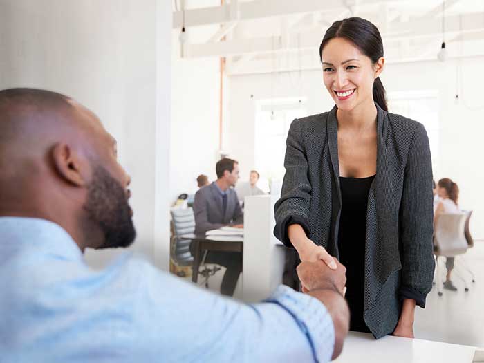 Woman shaking hands with a black businessman at an office meeting