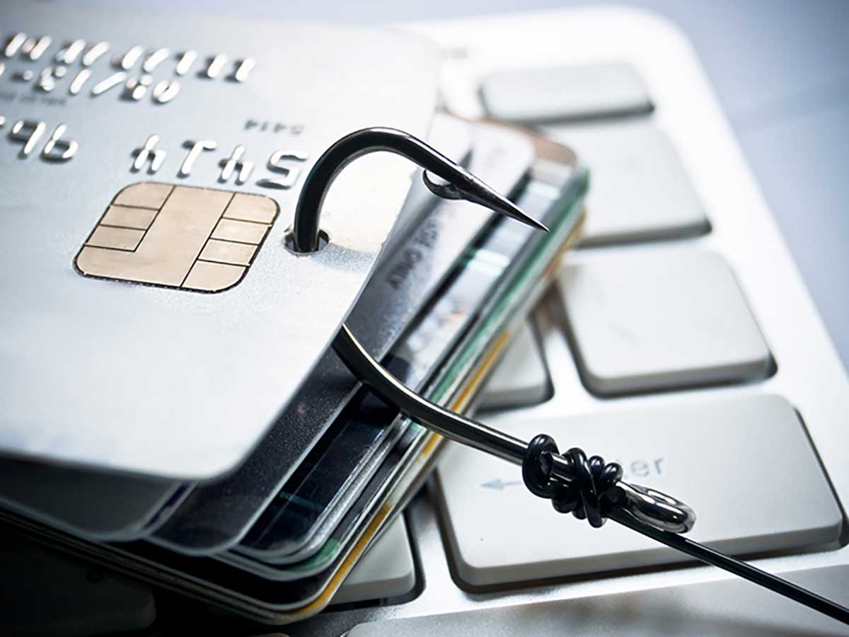 Stack of credit cards on computer keyboard, hooked with a sharp fishing hook 