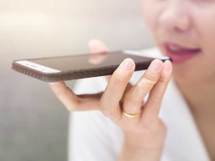 Close up of hand business girl using a smart phone voice recognition with a warm light background.
