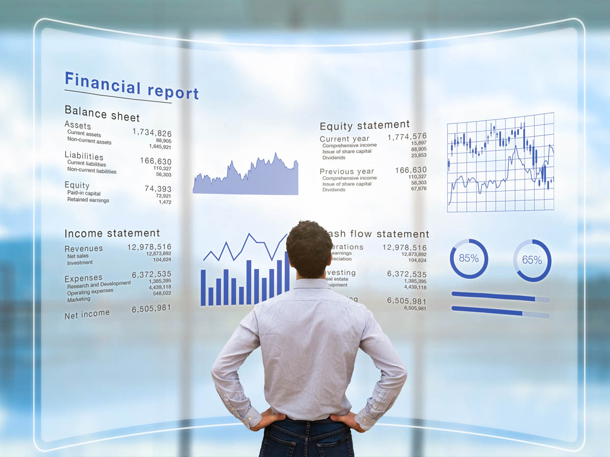 Homme d'affaires devant grand écran transparent, analysant les différentes données financières des opérations d'une entreprise