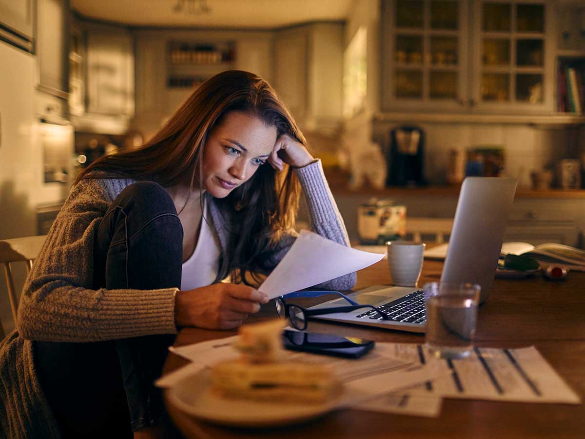 Conerned looking young woman sitting in kitchen looking over finances