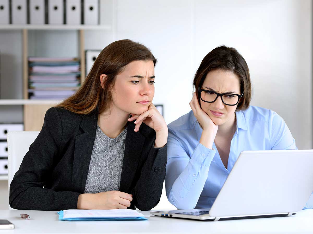 Deux employés de bureau confus examinant des informations en ligne sur un ordinateur portable de l'entreprise