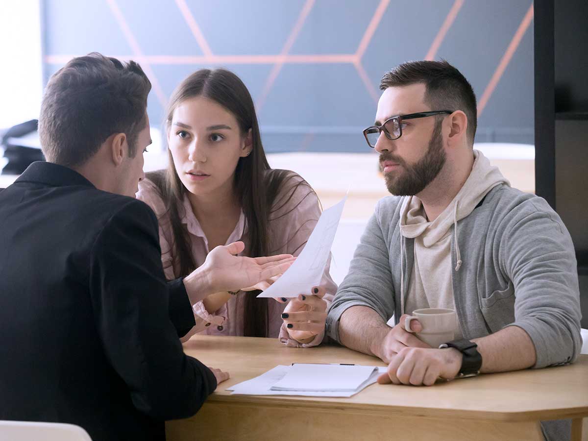 Millennial couple meeting with lawyer disputing contract terms