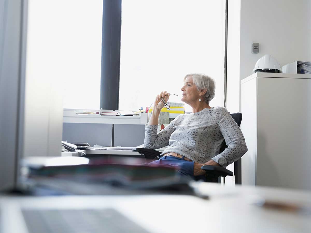 Pensive businesswoman sitting in office desk looking out the window