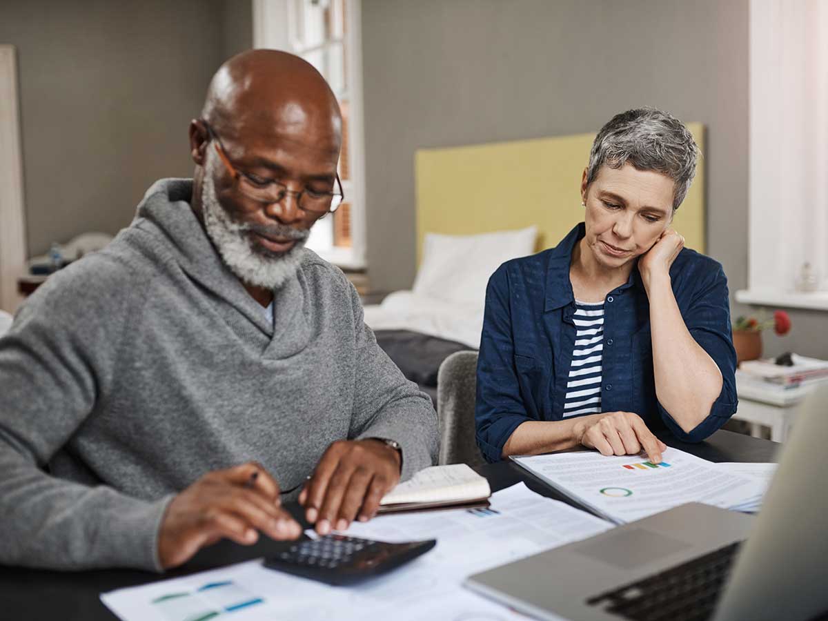 senior couple using laptop and a calculator to go over their finances together