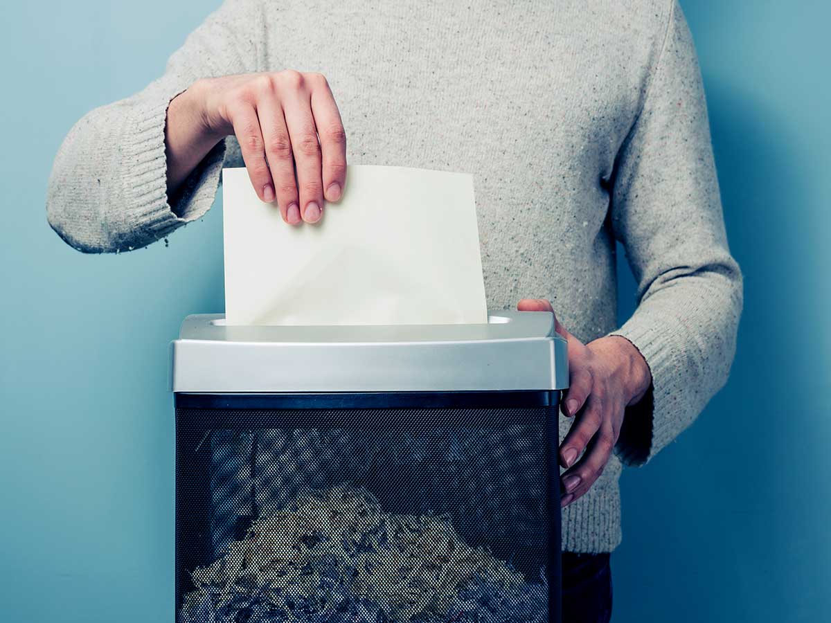 young person shredding documents, using a paper shredder