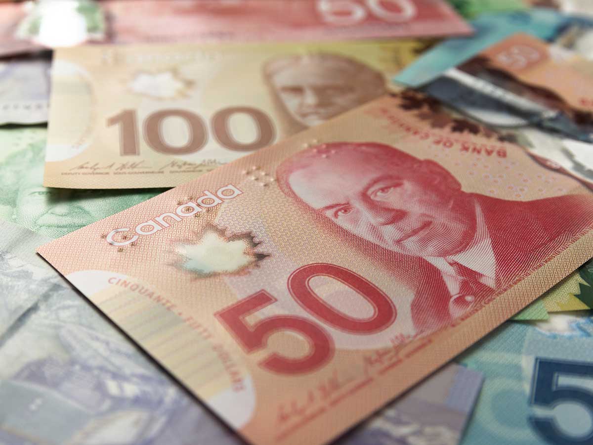 Close up of Canadian paper currency of different amounts spread on a table