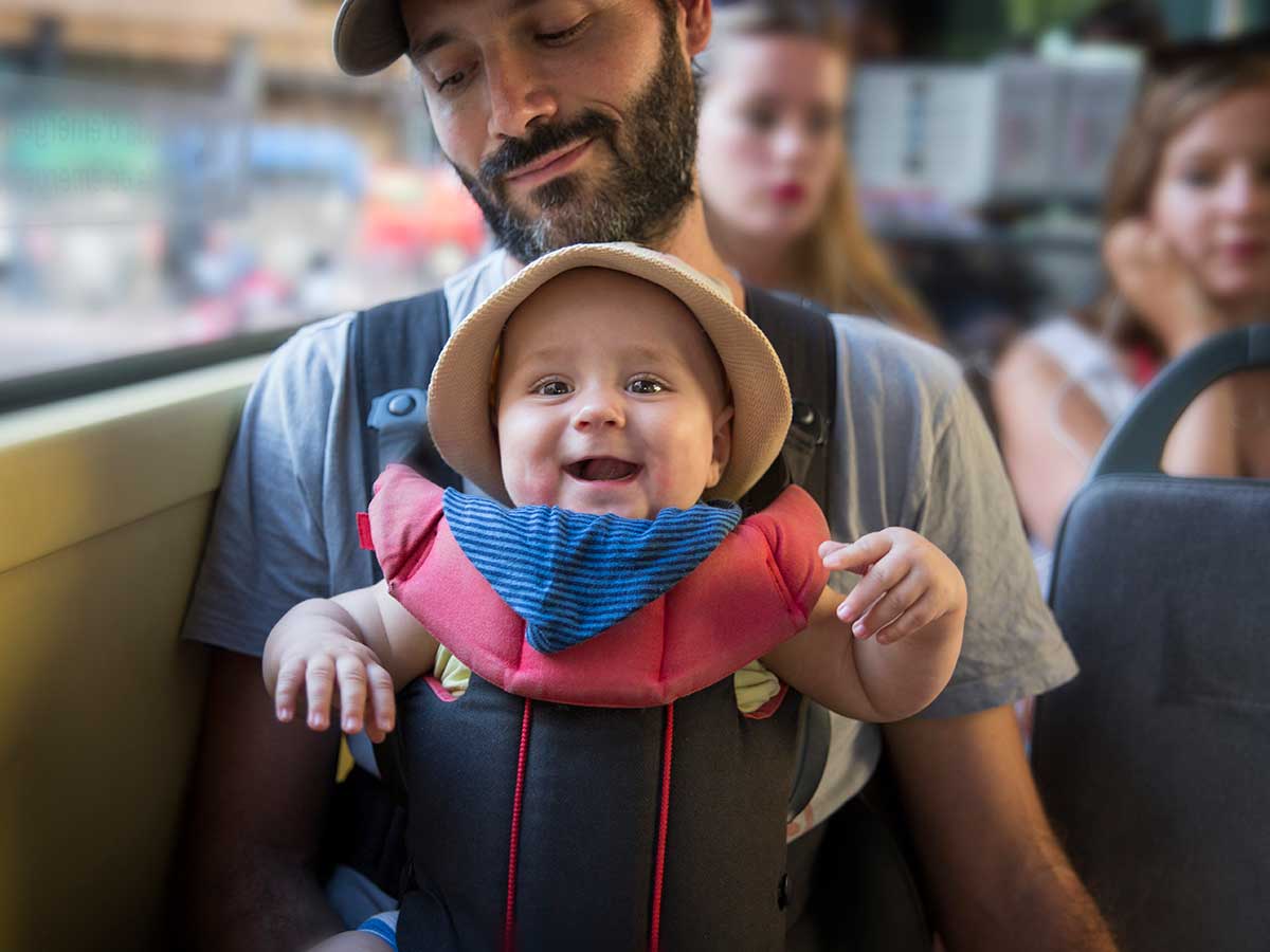 A baby travelling with it's father on a public bus