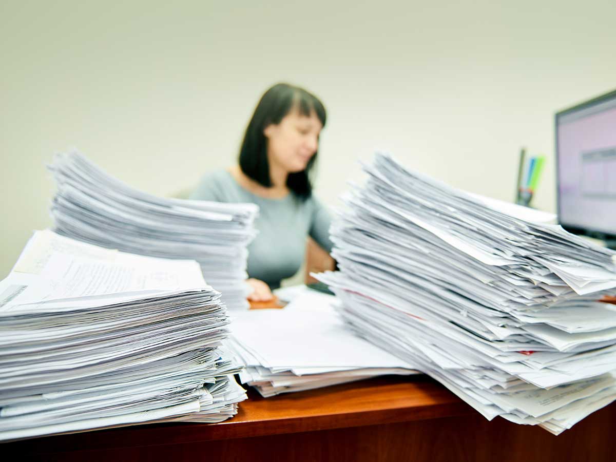 Femme comptable entourée de piles de documents papier