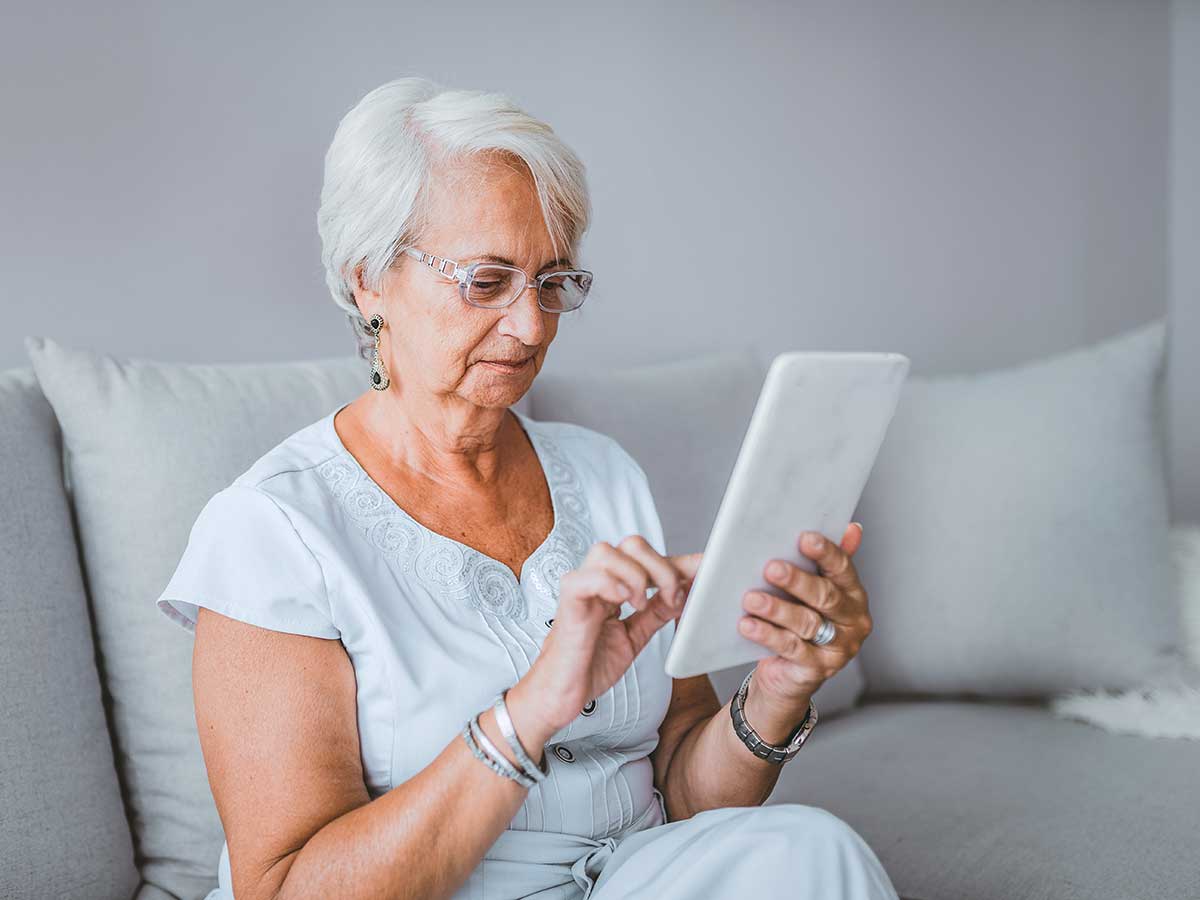 Elder lady using a tablet in her livingroom