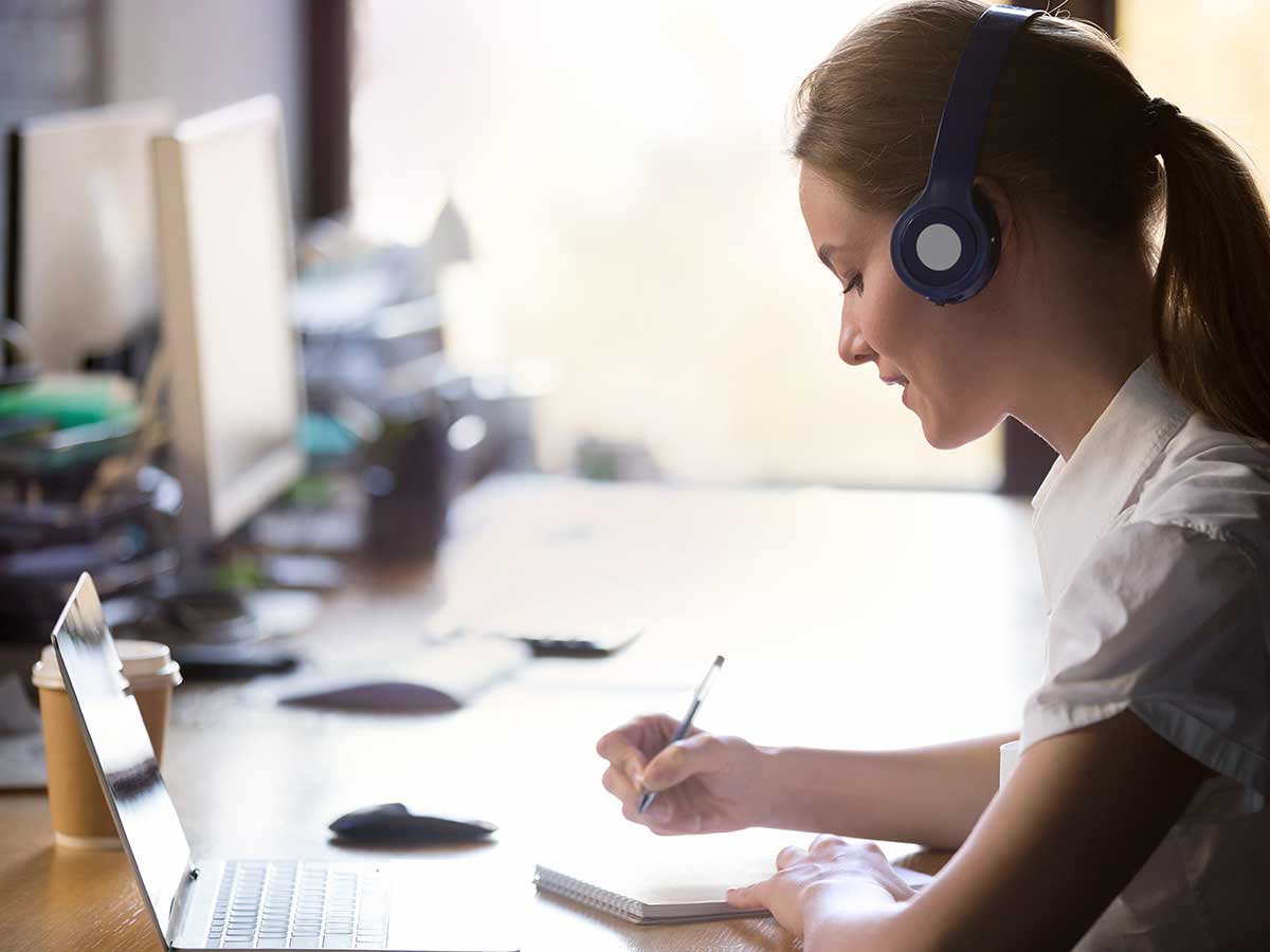 Young woman wearing headphones, while working at office desk