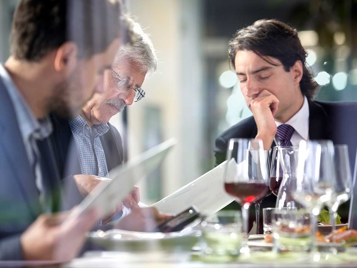 Business people having lunch at restaurant while studying business paperwork