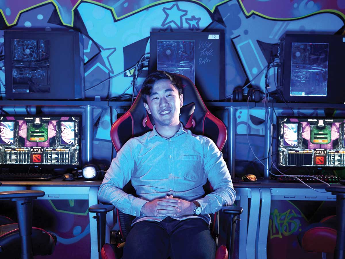 portrait of Deloitte’s Luc Ryu sitting among video-game stations