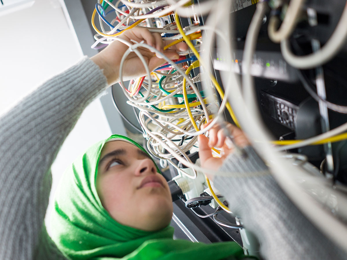 young Muslim woman working as technician, servicing a office server