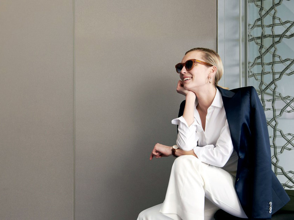 female model wearing white business suit and dark jacket while wearing sunglasses