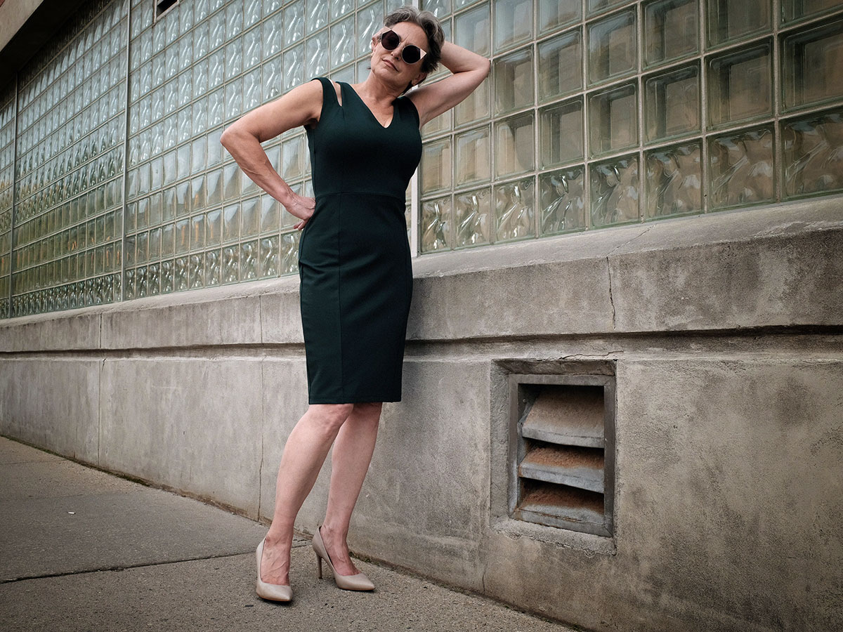 female model wearing a dress while standing outside on city sidewalk