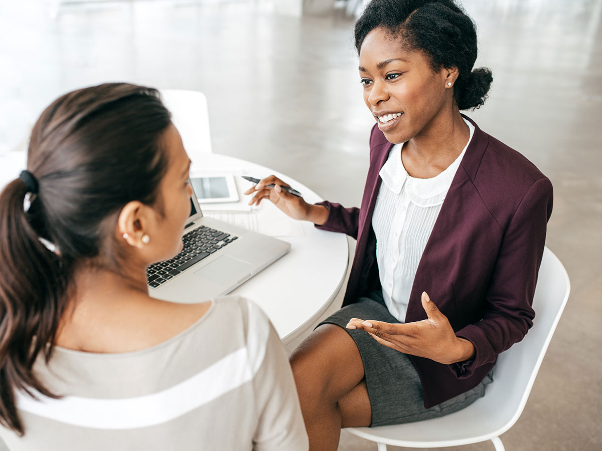 young business woman consulting another woman at a small table in an office environment 