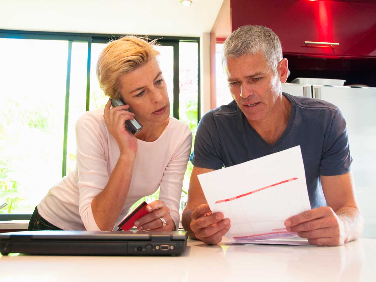 Couple looking at bill, holding credit card and talking on phone