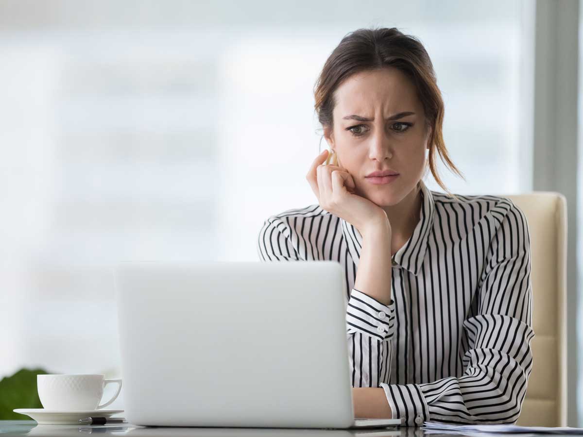 Femme d'affaires regarde son ordinateur portable avec confusion