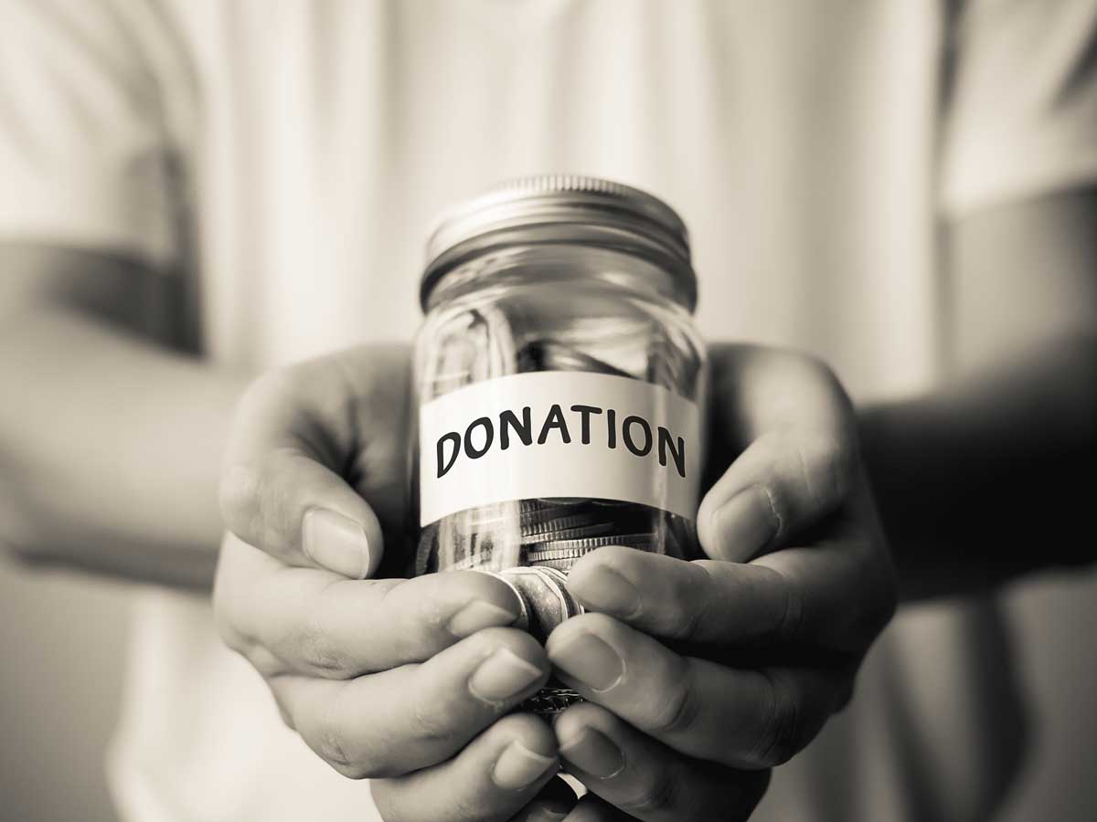 Hands holding a glass bottle with a note showing donations with money inside