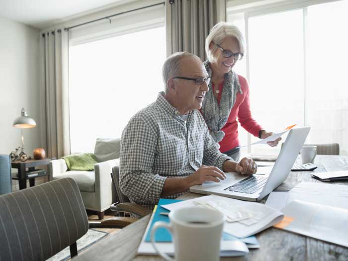 Couple de personnes âgées avec ordinateur portable, payer les factures en ligne dans la salle à manger
