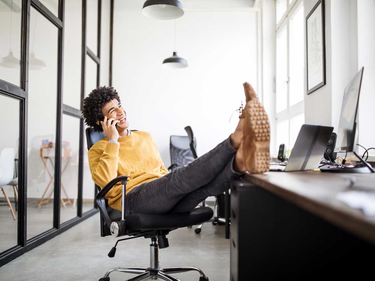Homme d'affaires détendu, parler au téléphone au bureau avec les pieds sur le bureau