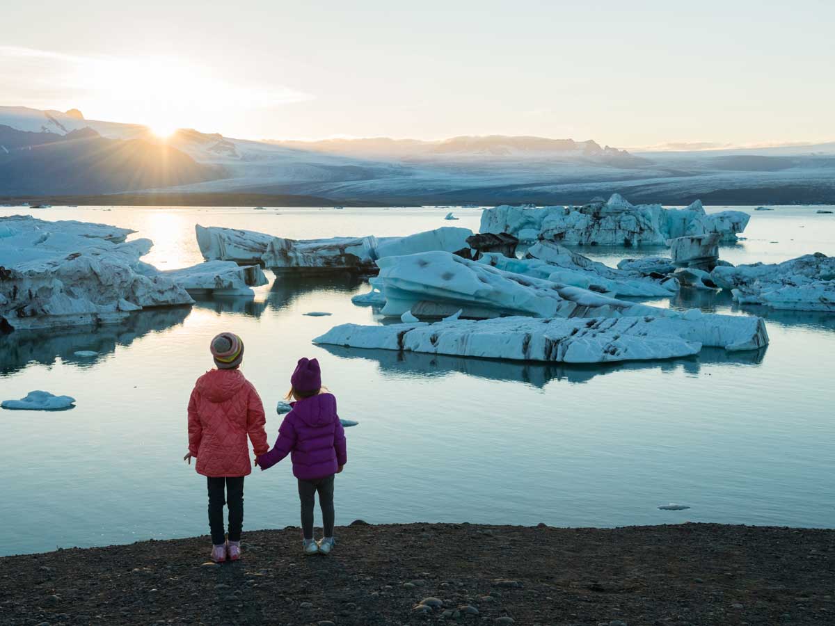 Kids standing on shore looking at melting glaciers