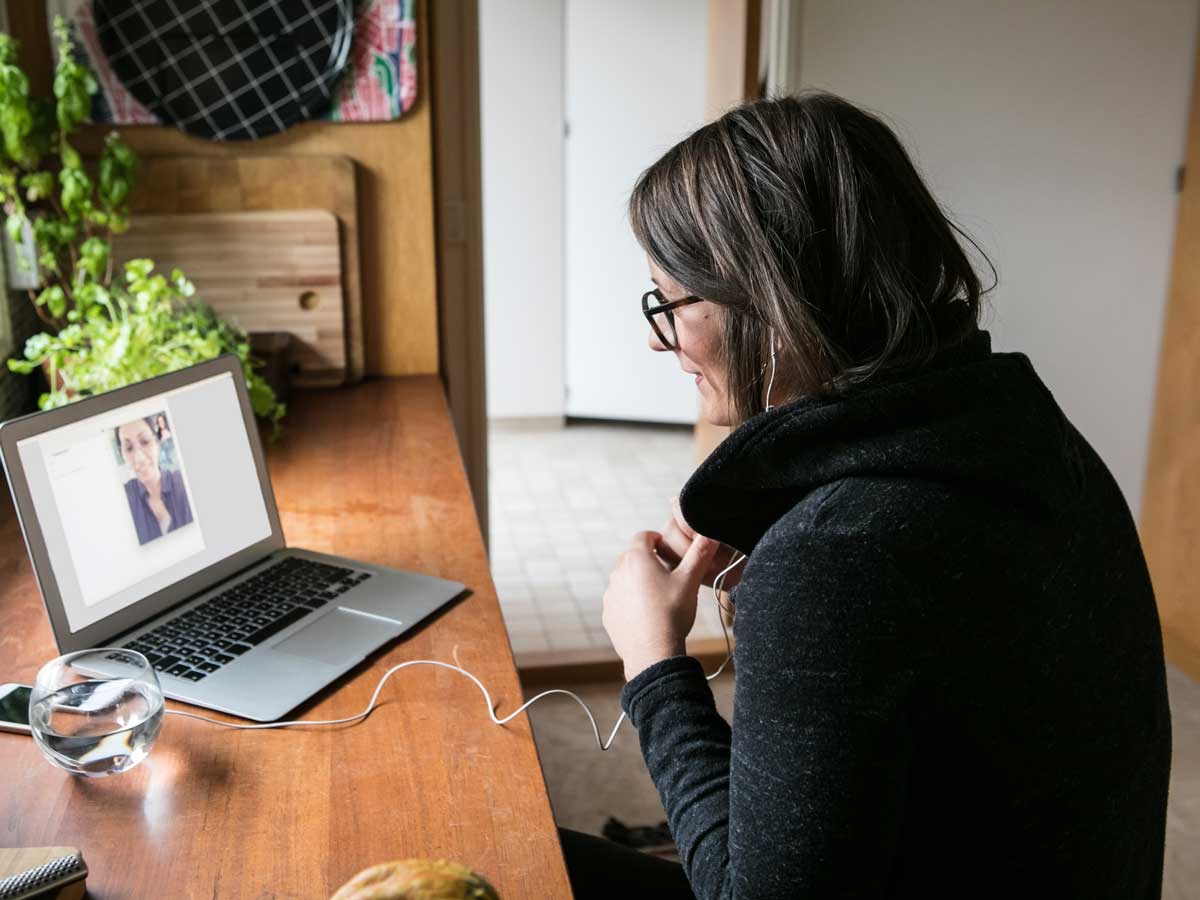 Vue de côté d'une femme d'affaire en train de faire un appel en vidéoconférence depuis un ordinateur