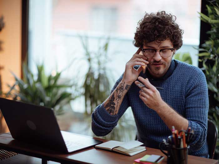 Jeune homme parlant au téléphone dans son bureau à domicile