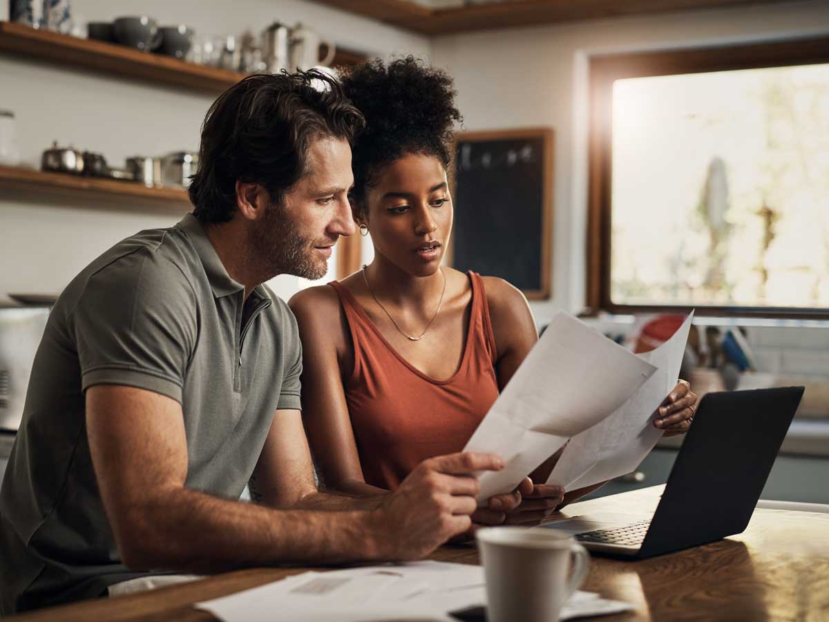 Man and woman looking over bills and laptop together
