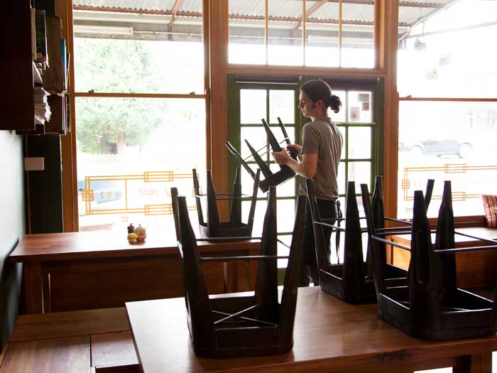 Waiter packing up cafe or restaurant chairs