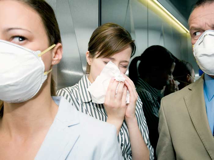 People on an elevator with face masks looking at someone who sneezes