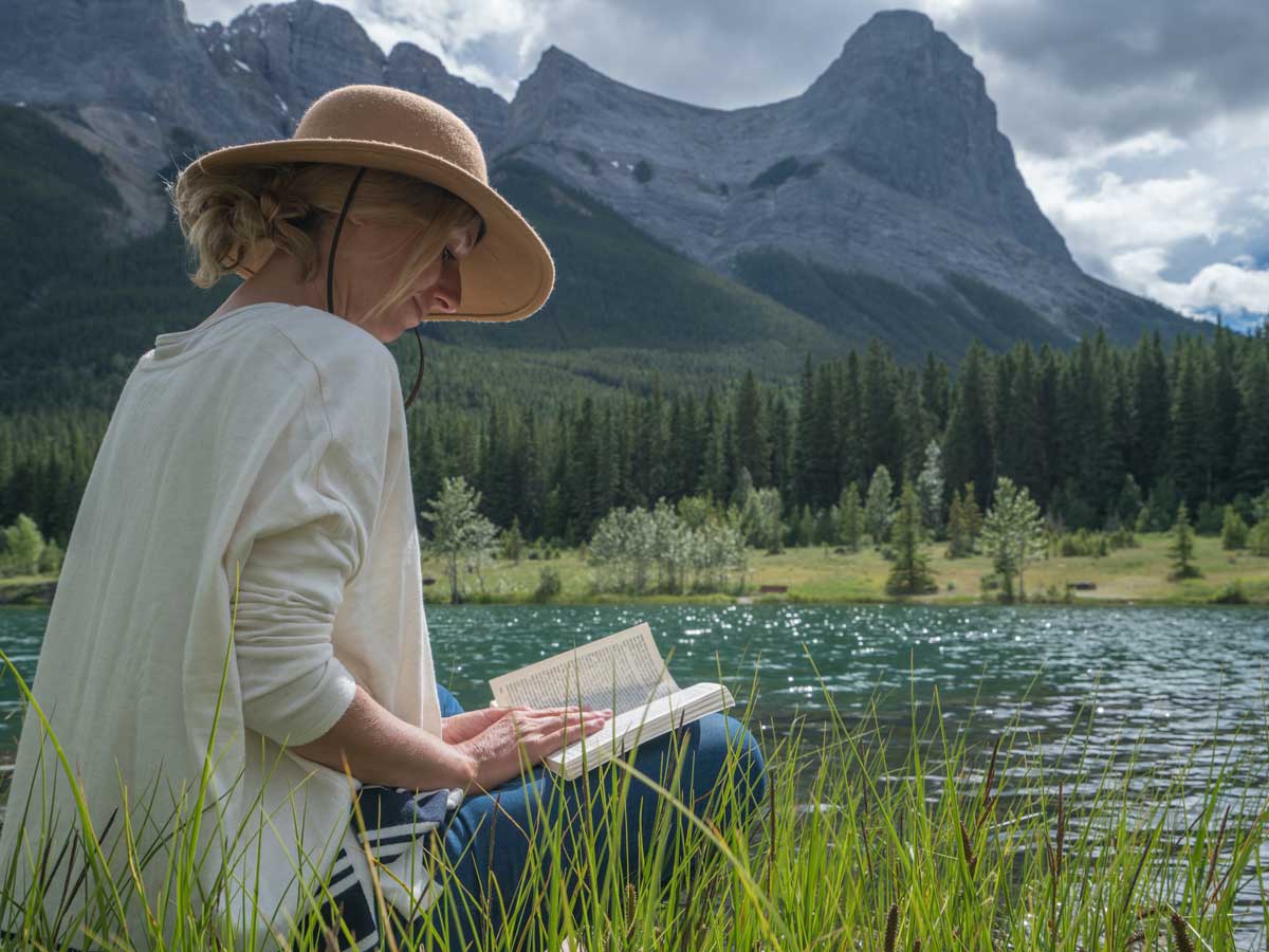 Jeune femme lisant un livre au bord du lac