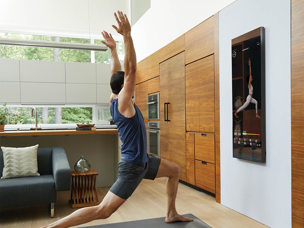 Man following yoga class on Mirror's wall-mounted screen