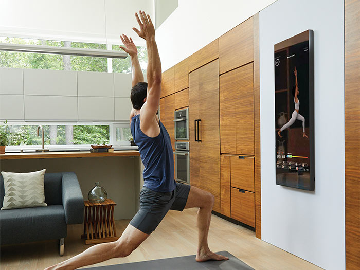 Homme suivant un cours de yoga sur l'écran mural de Mirror