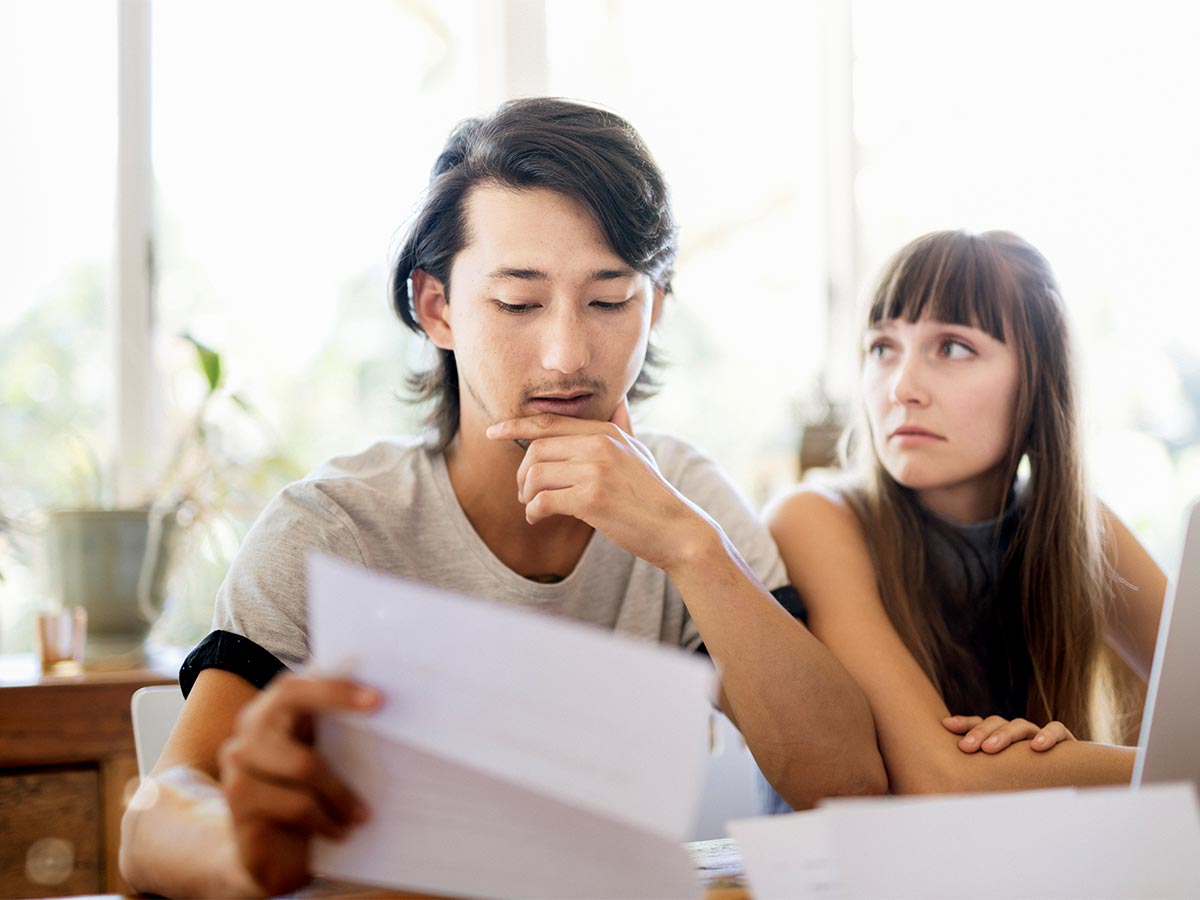 Worried young couple reading document at home