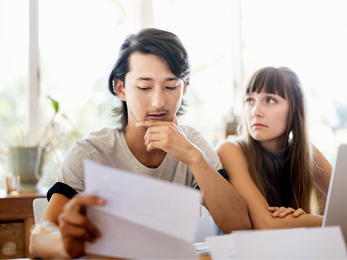 Worried young couple reading document at home