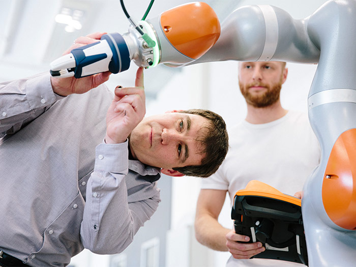 Two engineers work on a robotic arm
