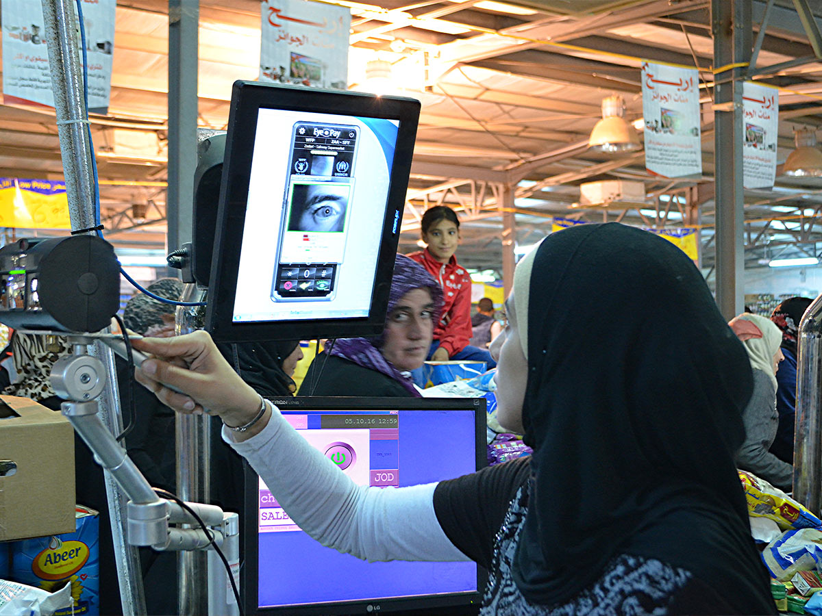 A cashier scans a refugee’s iris to purchase food at a refugee camp in Syria.