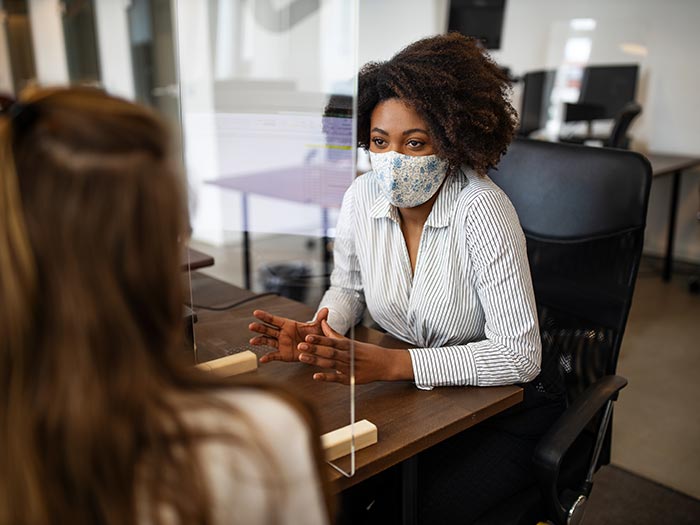 Businesswomen wearing protective face masks for protection against virus while working in office.