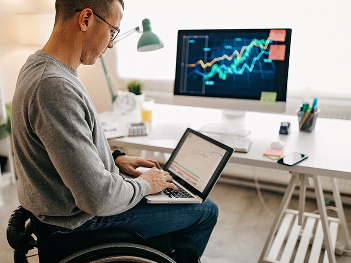 Young man in a wheelchair working on his stock market portfolio