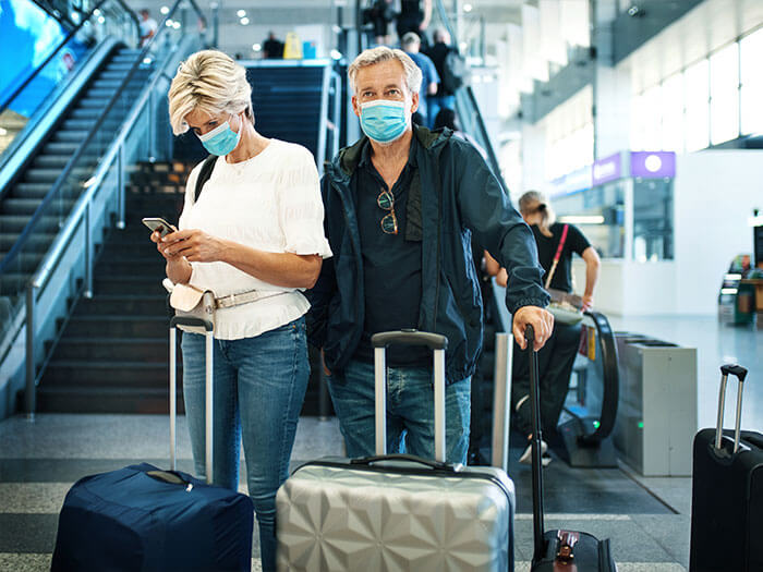 Couple wearing masks in airport surrounded by suitcases
