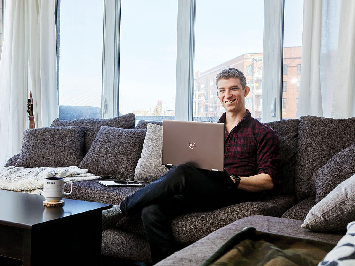 Le CPA Joshua Faier assis sur un canapé avec un ordinateur portable