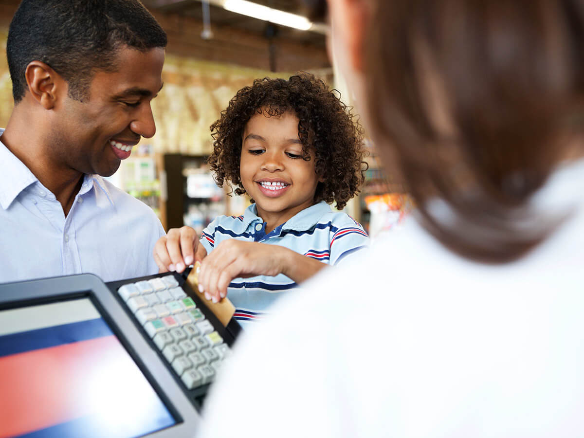 Un garçon utilise la carte de crédit de son père dans un supermarché