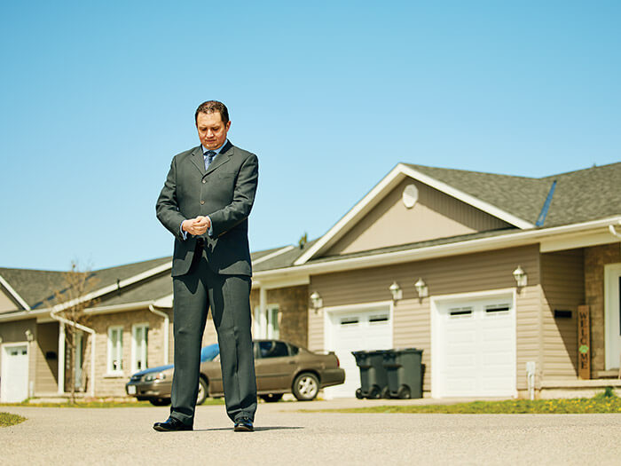 CPA Justin Marchand adjusts the cuff of his suit while standing in a home driveway