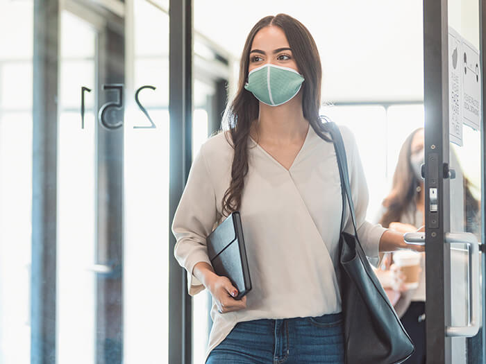 Businesswoman wears a protective mask as she enters an office building