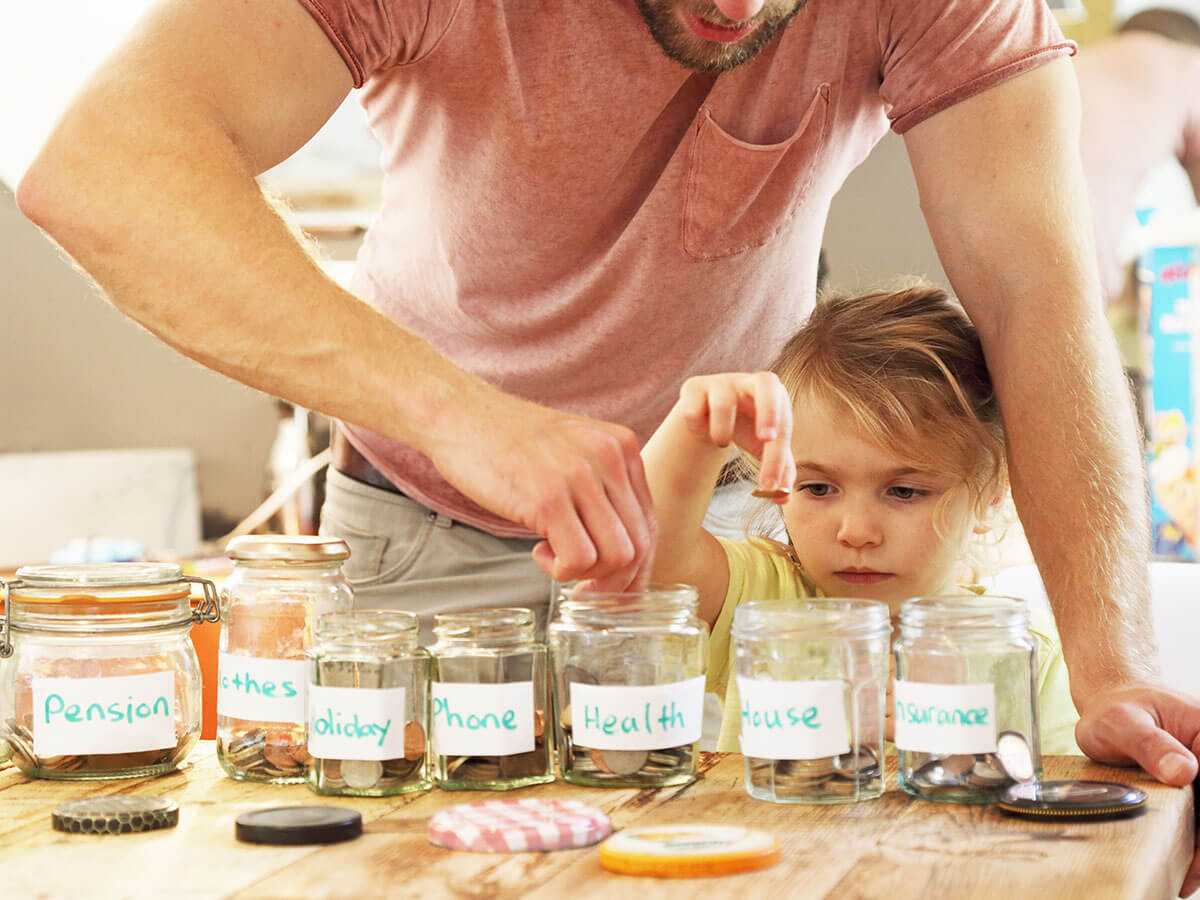 Une jeune fille est représentée en train de mettre des pièces dans des pots d'épargne étiquetés avec son père