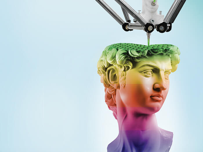 Une imprimante 3D crée la sculpture d'une tête aux couleurs de l'arc-en-ciel.